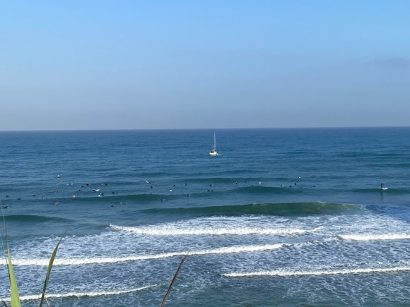 A photo of a yacht in the distance and surfers in the sea